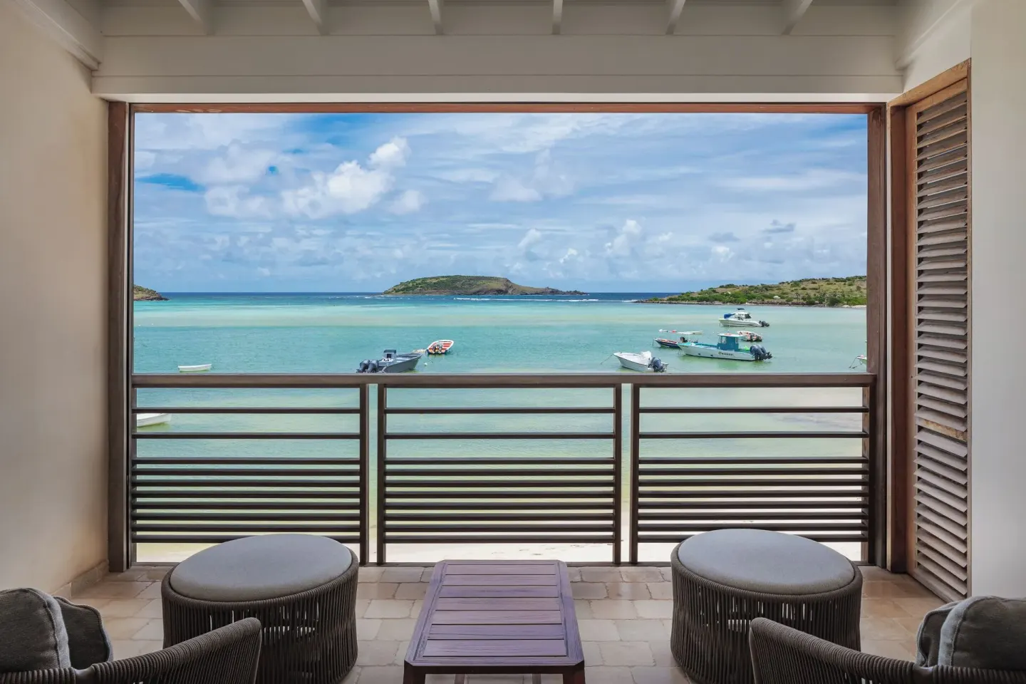 Balcony seating overlooking turquoise water and boats at Le Barthélemy Hotel & Spa.