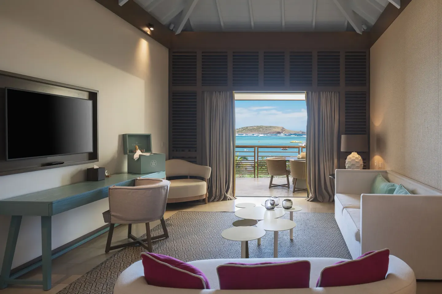 Guest room lounge with balcony and bay view at Le Barthélemy Hotel & Spa.