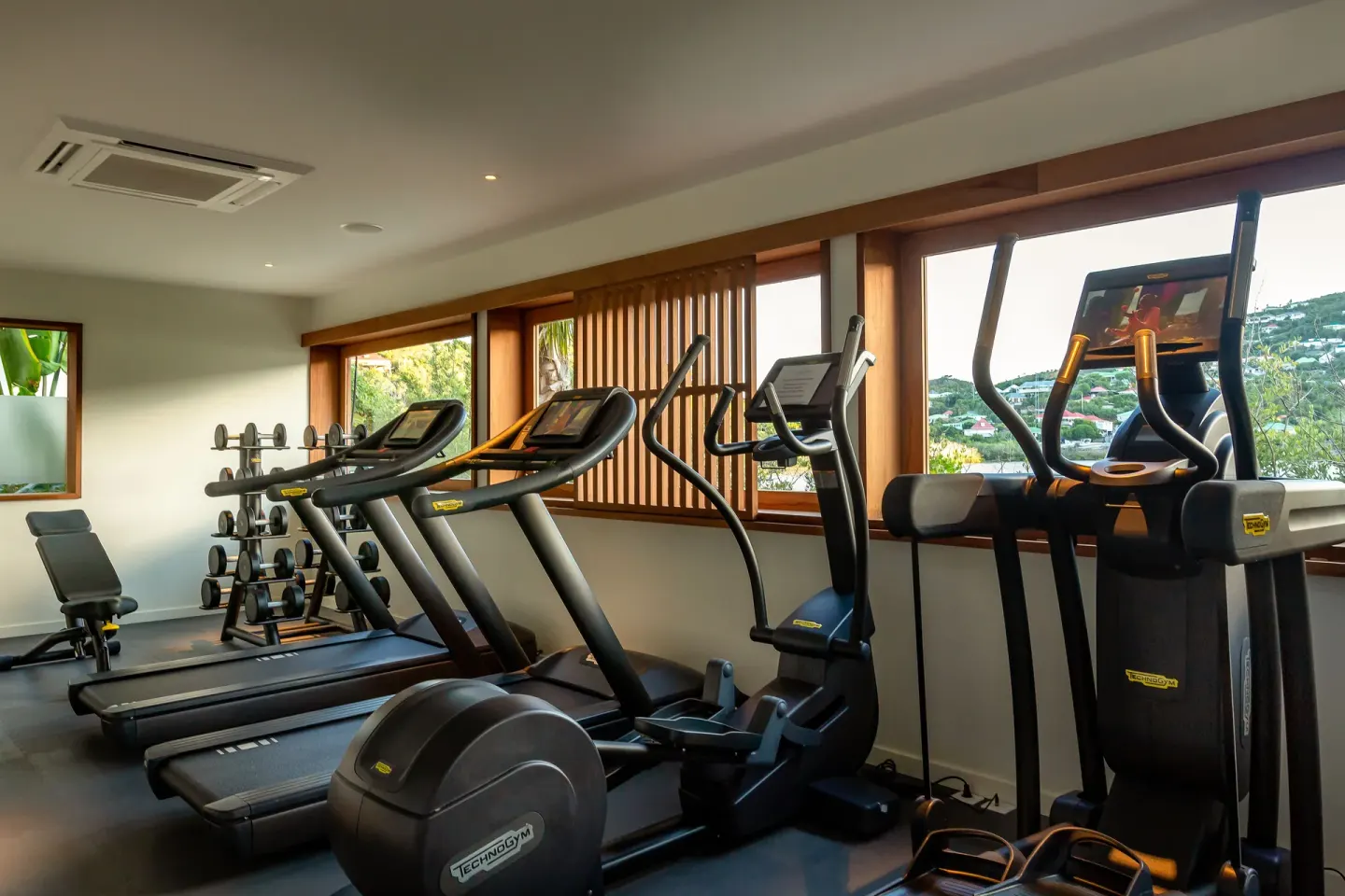 Fitness room with treadmills, elliptical machines and dumbbells at Le Barthélemy Hotel & Spa.