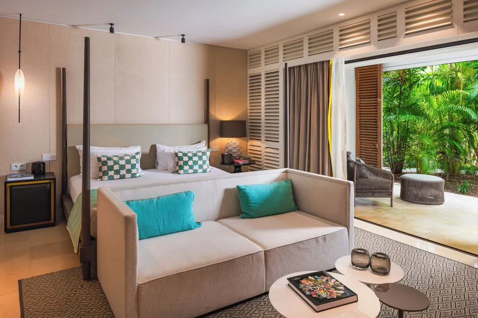 Garden-facing guest room with king bed and sofa at Le Barthélemy Hotel & Spa.