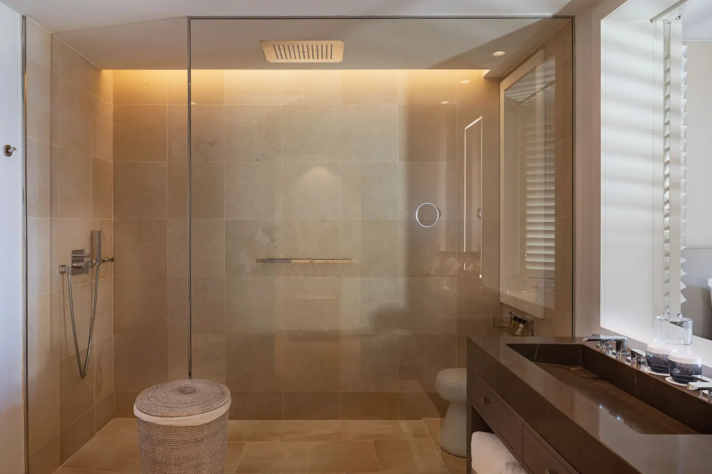 Bathroom shower with vanity and woven stool at Le Barthélemy Hotel & Spa.