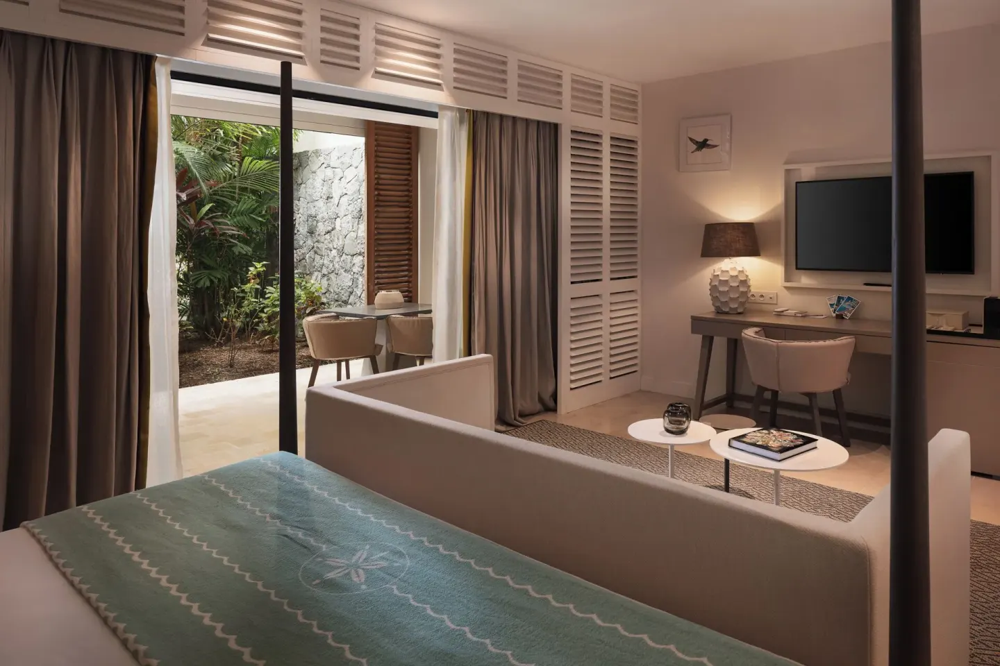 Guest room with bed, sitting area, desk, and garden patio at Le Barthélemy Hotel & Spa.