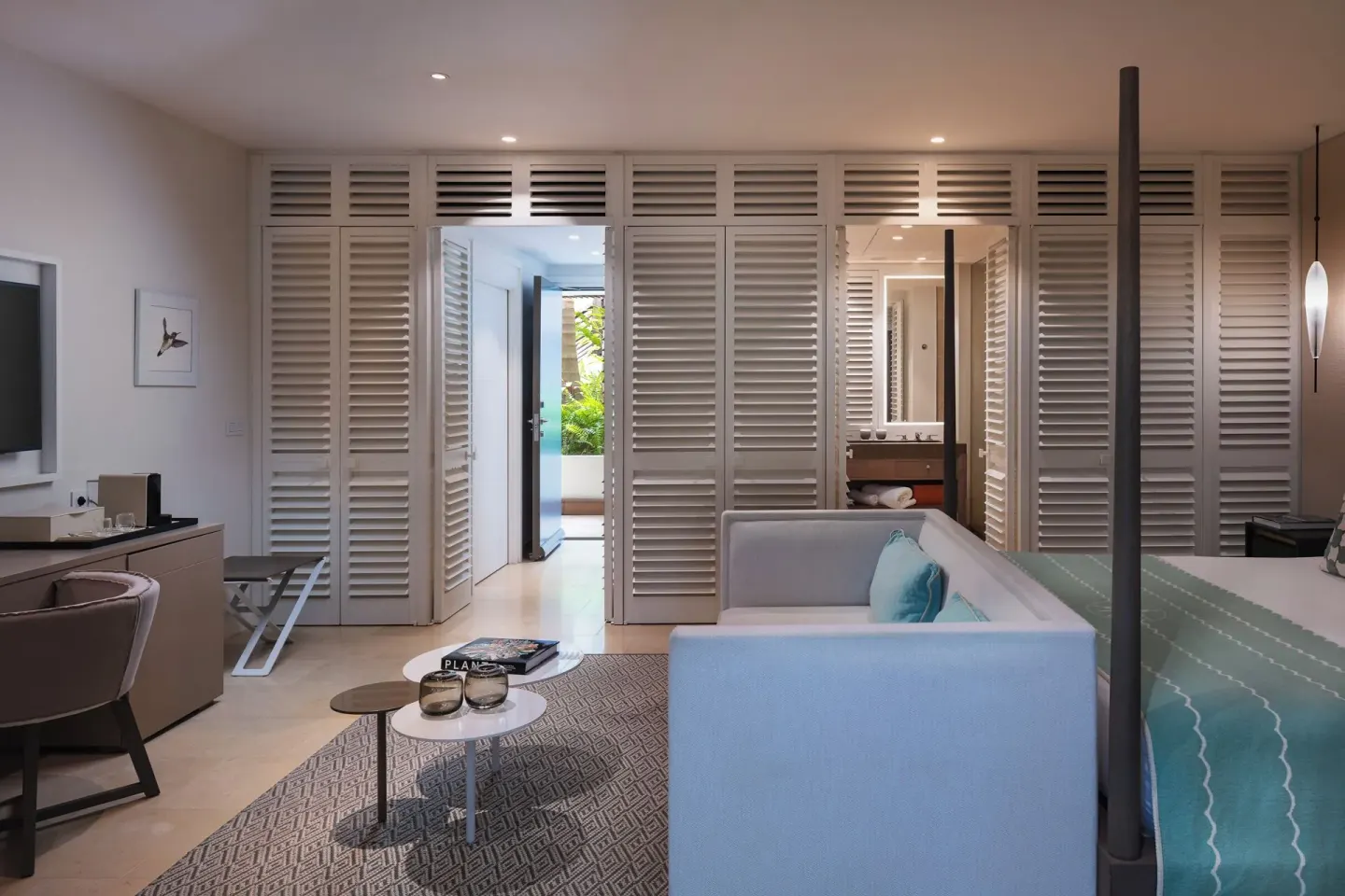 Guest room lounge, desk, and partial king bed at Le Barthélemy Hotel & Spa.