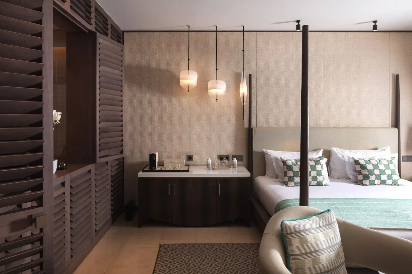 Guest room king bed with pendant lights and refreshment counter at Le Barthélemy Hotel & Spa.