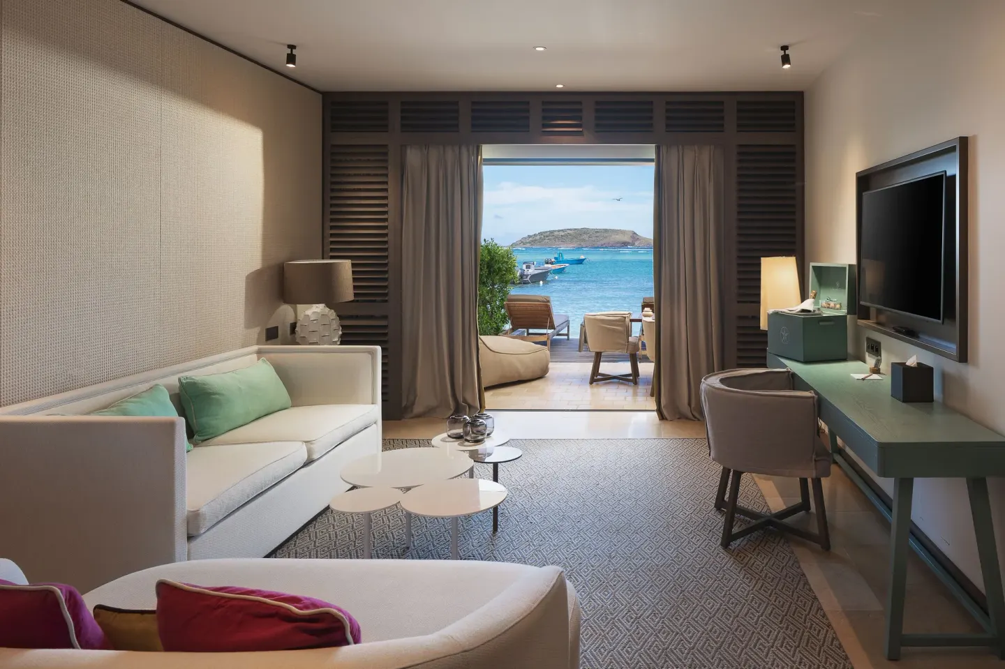 Ocean-view sitting area with sofa and desk at Le Barthélemy Hotel & Spa.