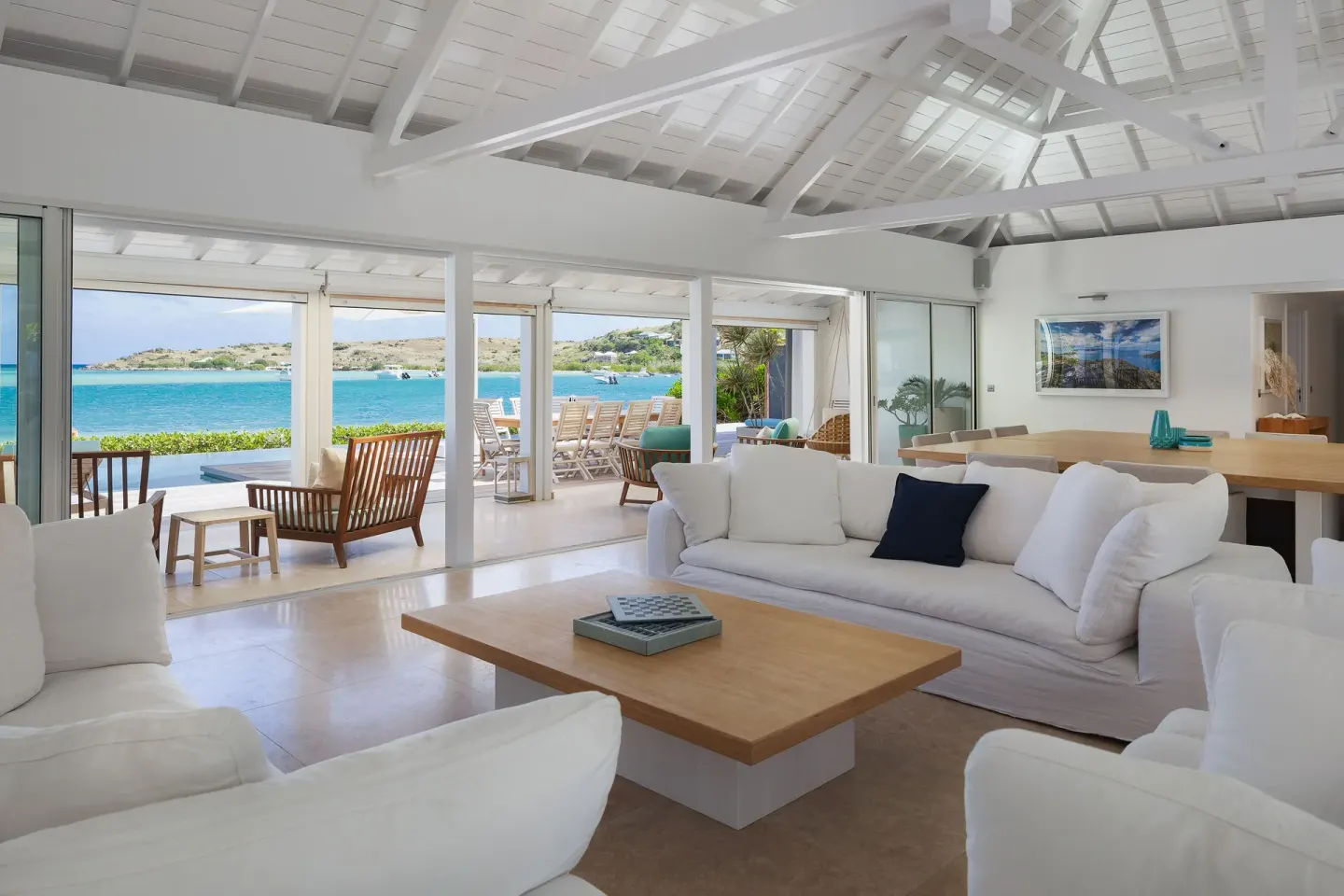 Oceanfront living room with white sofas and terrace doors at Le Barthélemy Hotel & Spa.