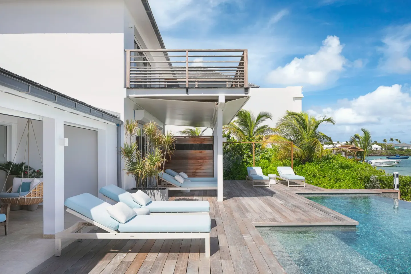 Pool deck with pale blue loungers and palms at Le Barthélemy Hotel & Spa.