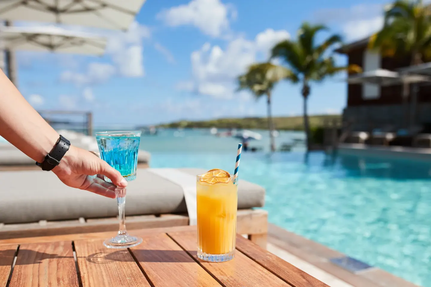 Poolside drinks on a wooden table at Le Barthélemy Hotel & Spa.
