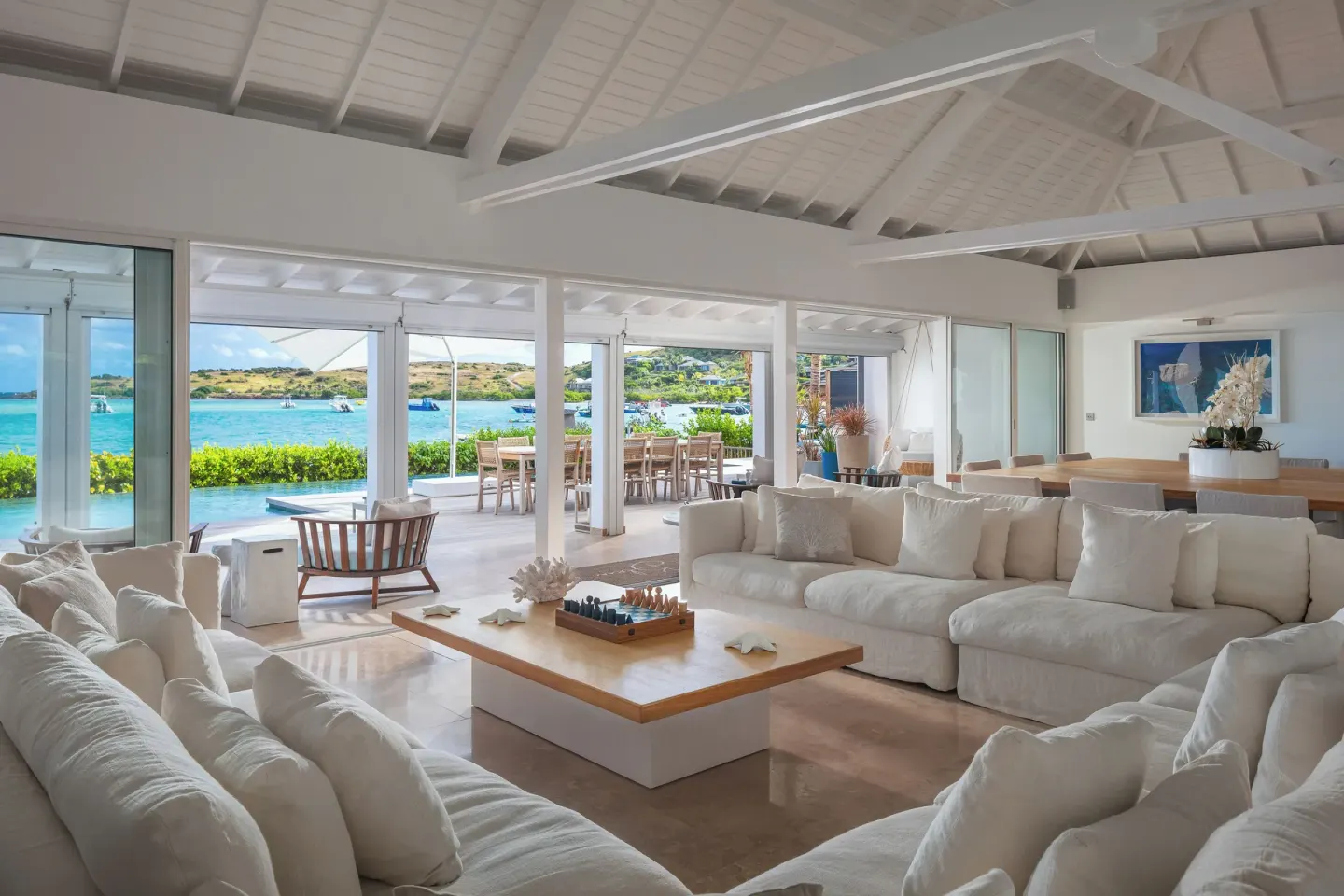 Bright waterfront lounge with white sofas at Le Barthélemy Hotel & Spa.