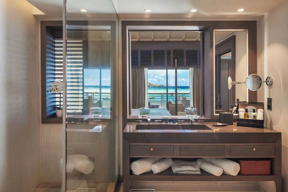 Junior Suite Océan bathroom vanity and shower with room beyond at Le Barthélemy Hotel & Spa.