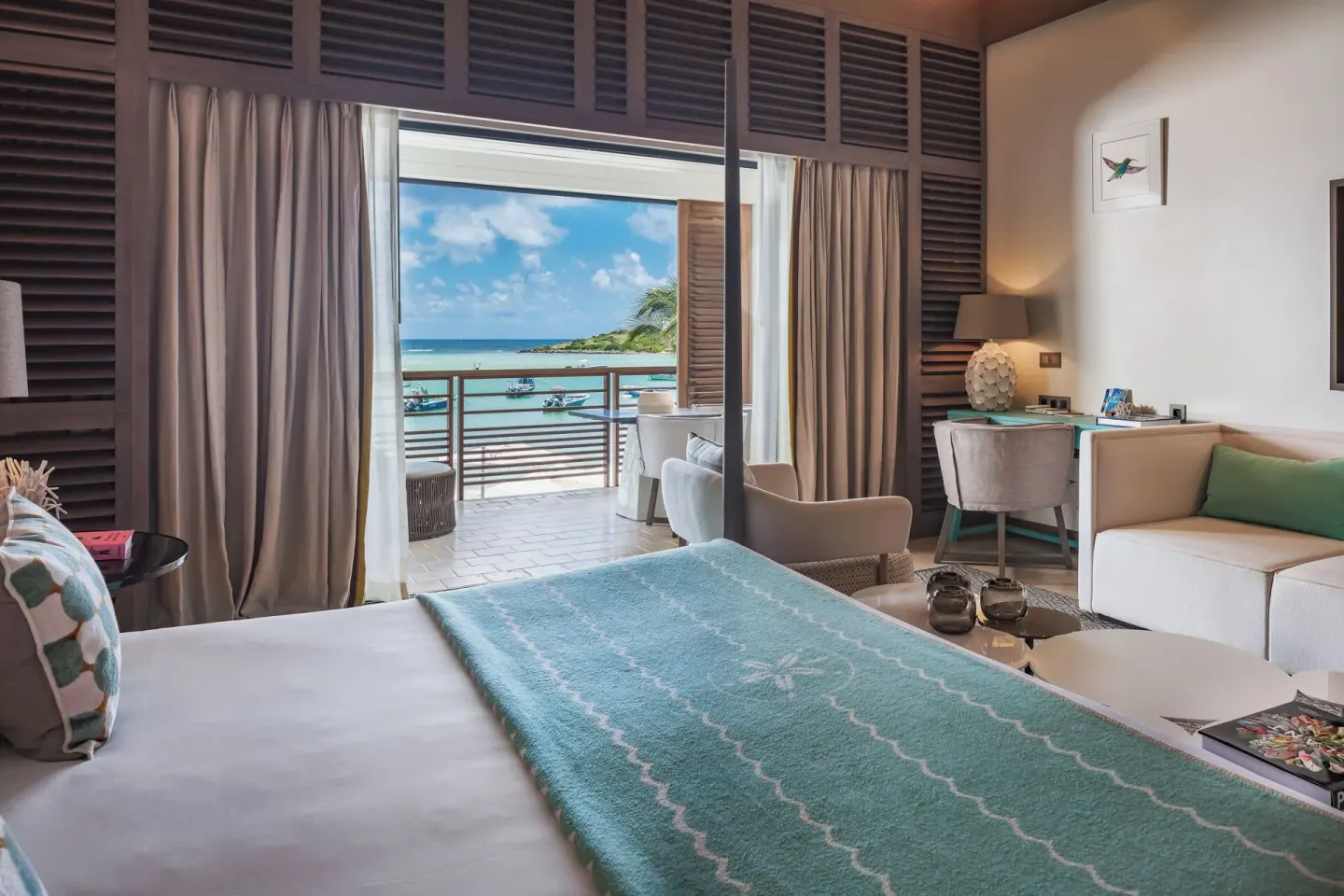 Junior Suite Océan bed, sofa, desk, and balcony view at Le Barthélemy Hotel & Spa.