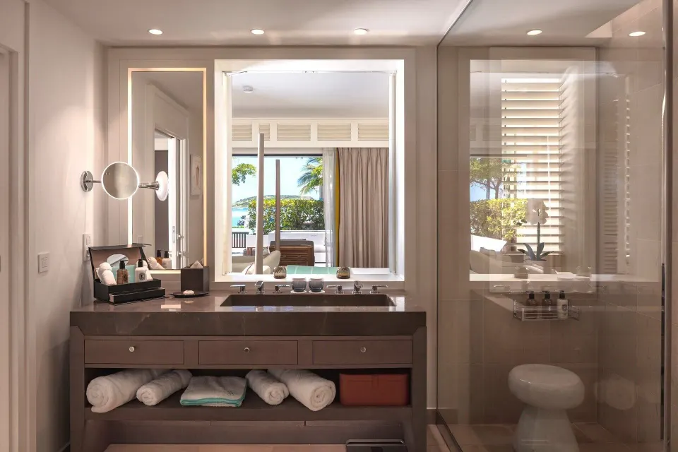 Le Barth Océan Jacuzzi bathroom at Le Barthélemy Hotel & Spa with vanity, towels, glass shower, and terrace view.