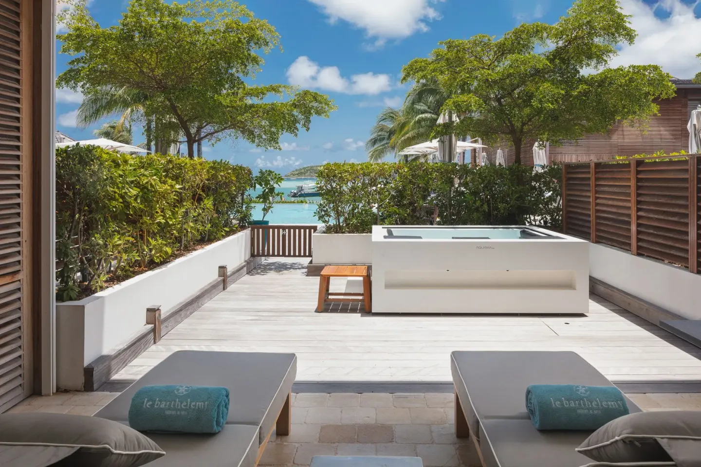 Le Barth Océan Jacuzzi terrace at Le Barthélemy Hotel & Spa with loungers, hot tub, greenery, and ocean view.
