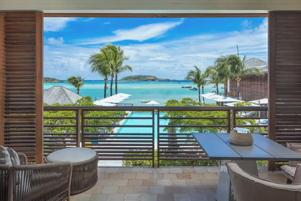 Furnished balcony with lagoon and ocean view at Le Barthélemy Hotel & Spa.