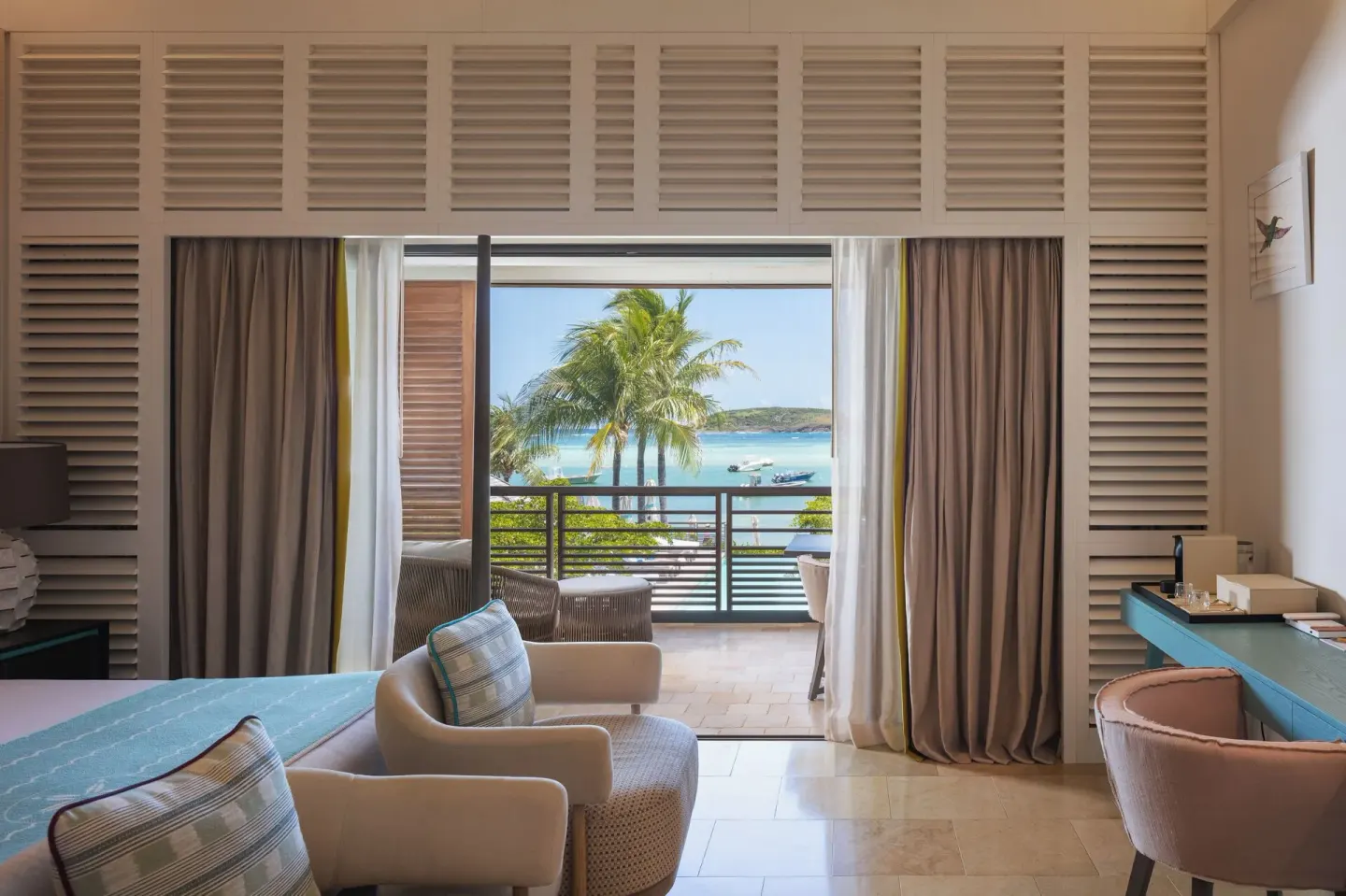 Ocean View room seating and balcony at Le Barthélemy Hotel & Spa with palms and turquoise water beyond.