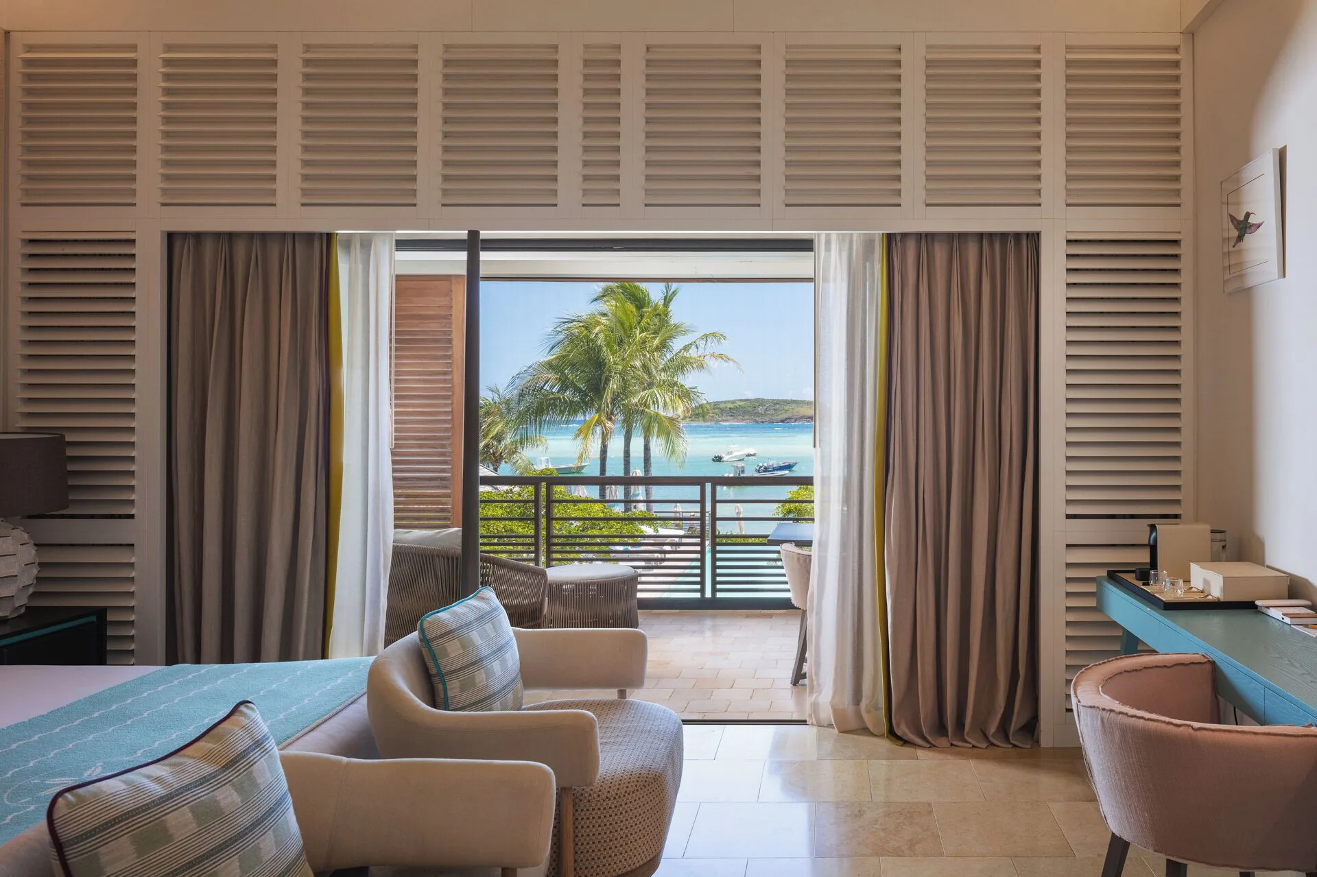 Ocean View room seating and balcony at Le Barthélemy Hotel & Spa with palms and turquoise water beyond.