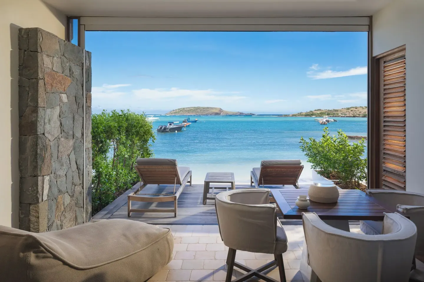 Beachfront terrace of Le Duplex Océan Plage at Le Barthélemy Hotel & Spa with loungers and lagoon view.