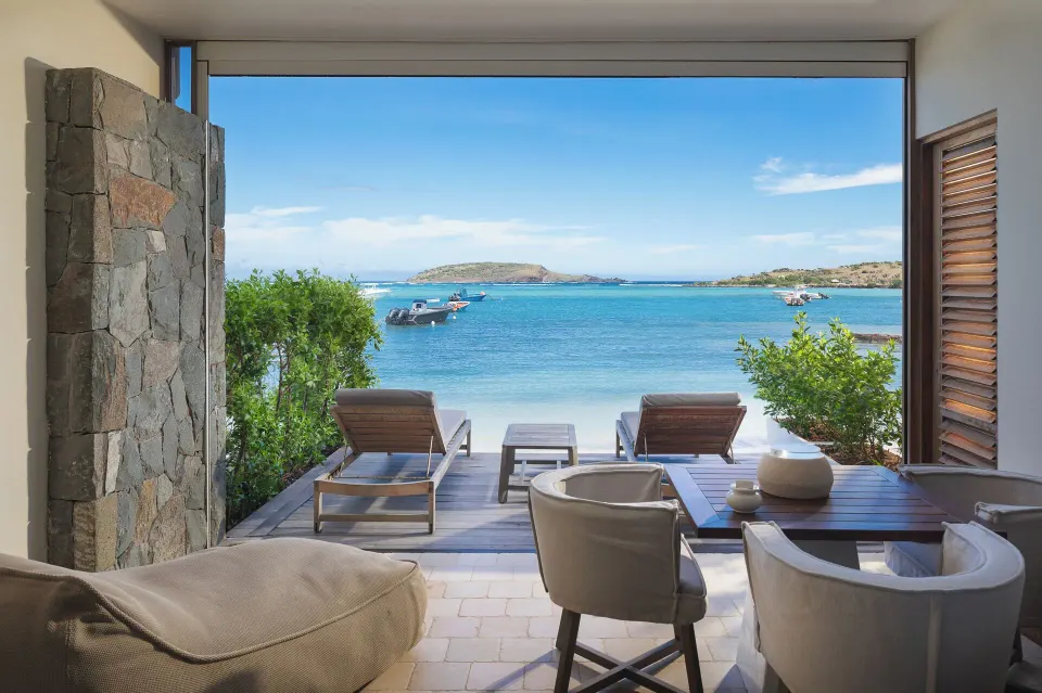 Beachfront terrace of Le Duplex Océan Plage at Le Barthélemy Hotel & Spa with loungers and lagoon view.