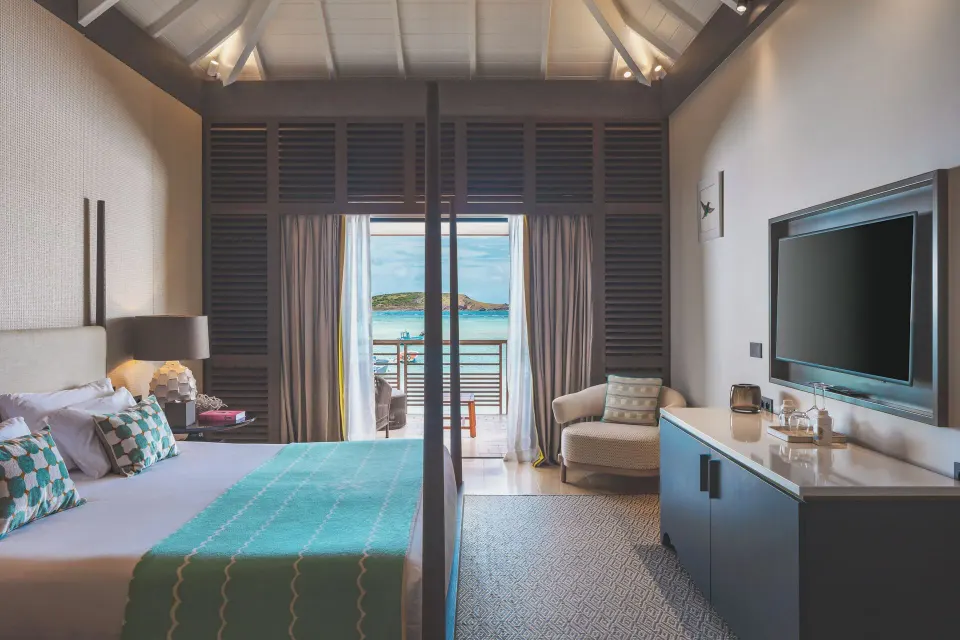 Le Duplex Océan Plage bedroom at Le Barthélemy Hotel & Spa with bed, TV, armchair, and sea view.