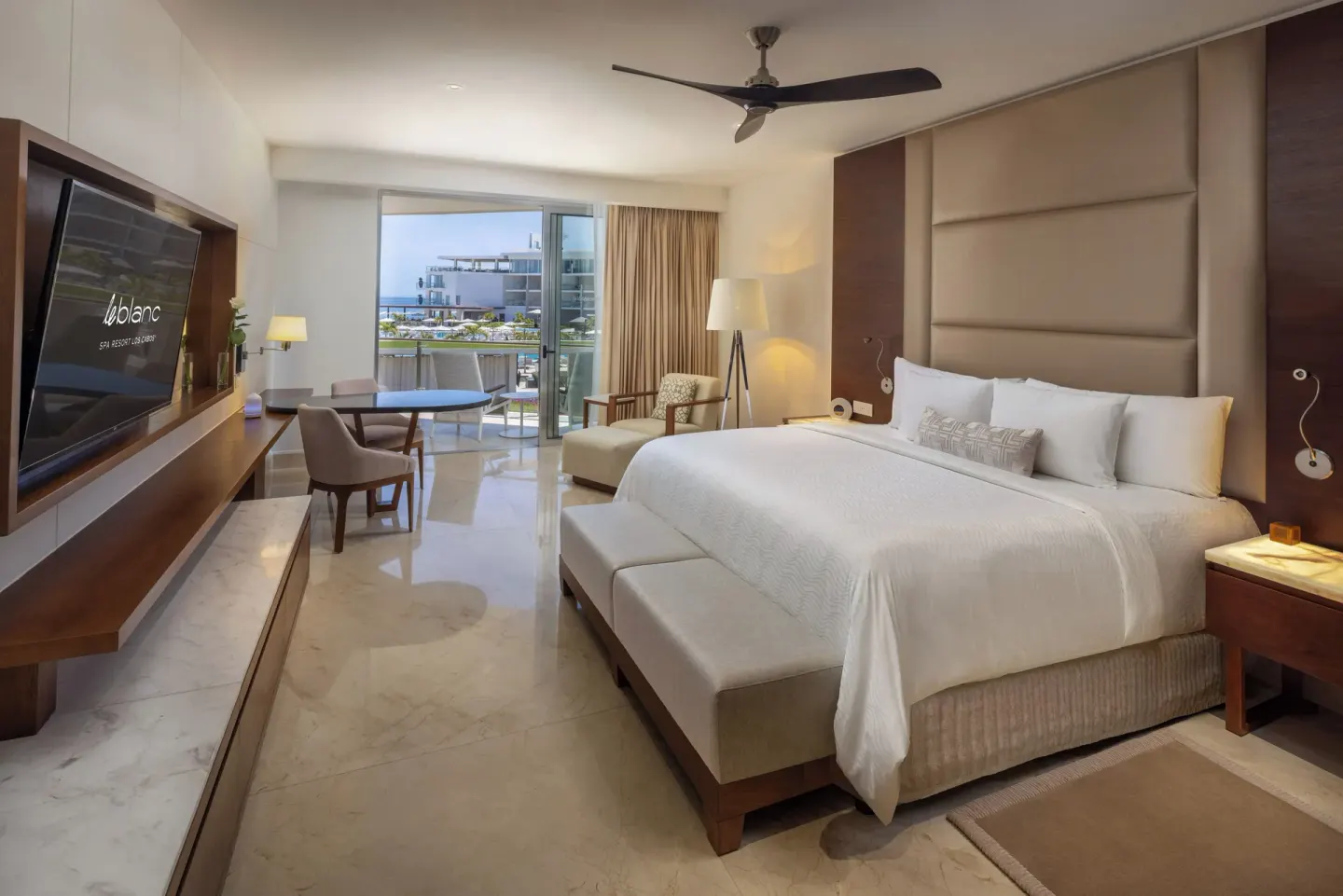 Royale Deluxe Partial Ocean View king room at Le Blanc Spa Resort Los Cabos with desk and balcony doors.
