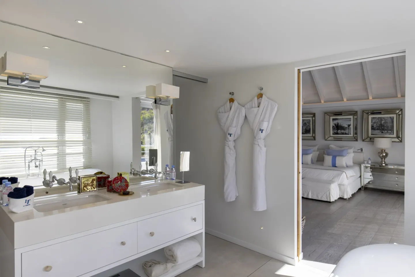 Bathroom vanity with robes and bedroom doorway at Le Toiny Hôtel & Beach Club.