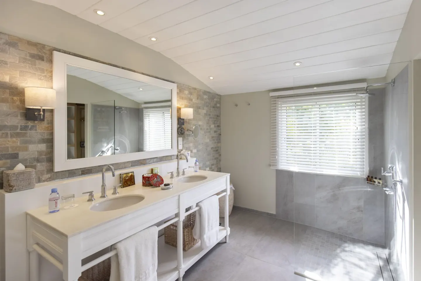 Stone-accent bathroom with double vanity and shower area at Le Toiny Hôtel & Beach Club.
