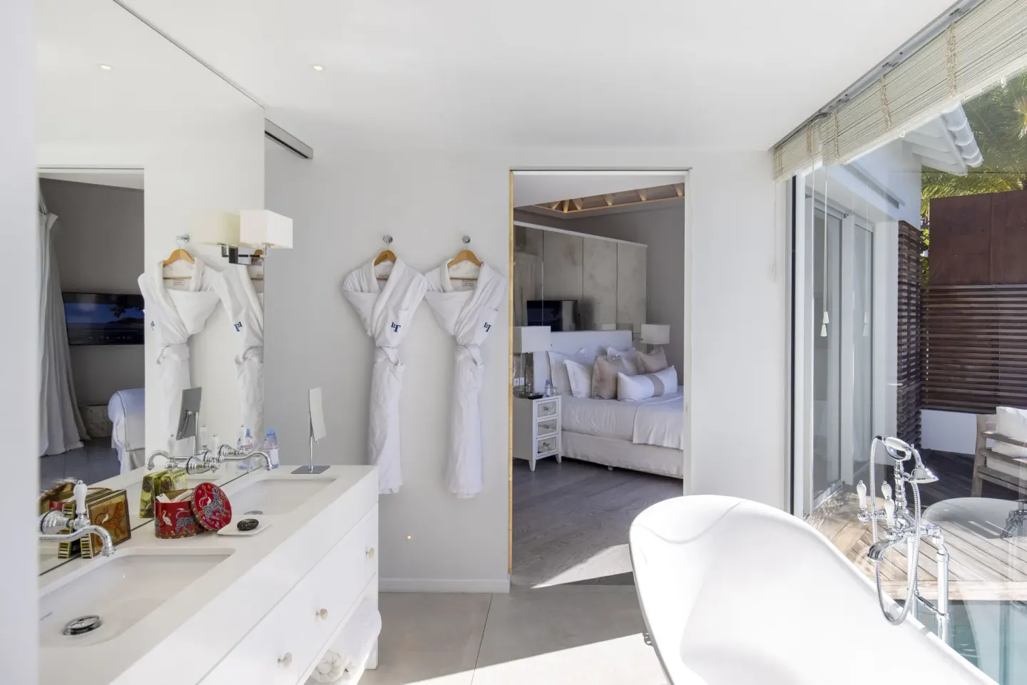 Bright bathroom with freestanding tub and robes at Le Toiny Hôtel & Beach Club.