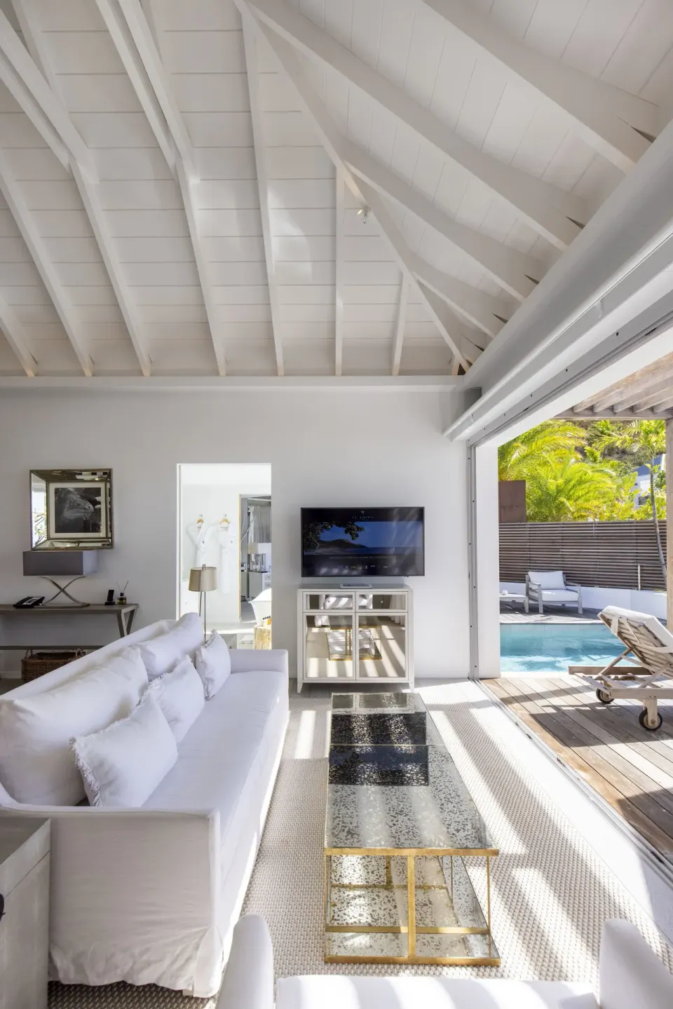 High-ceiling villa living room beside a pool deck at Le Toiny Hôtel & Beach Club.