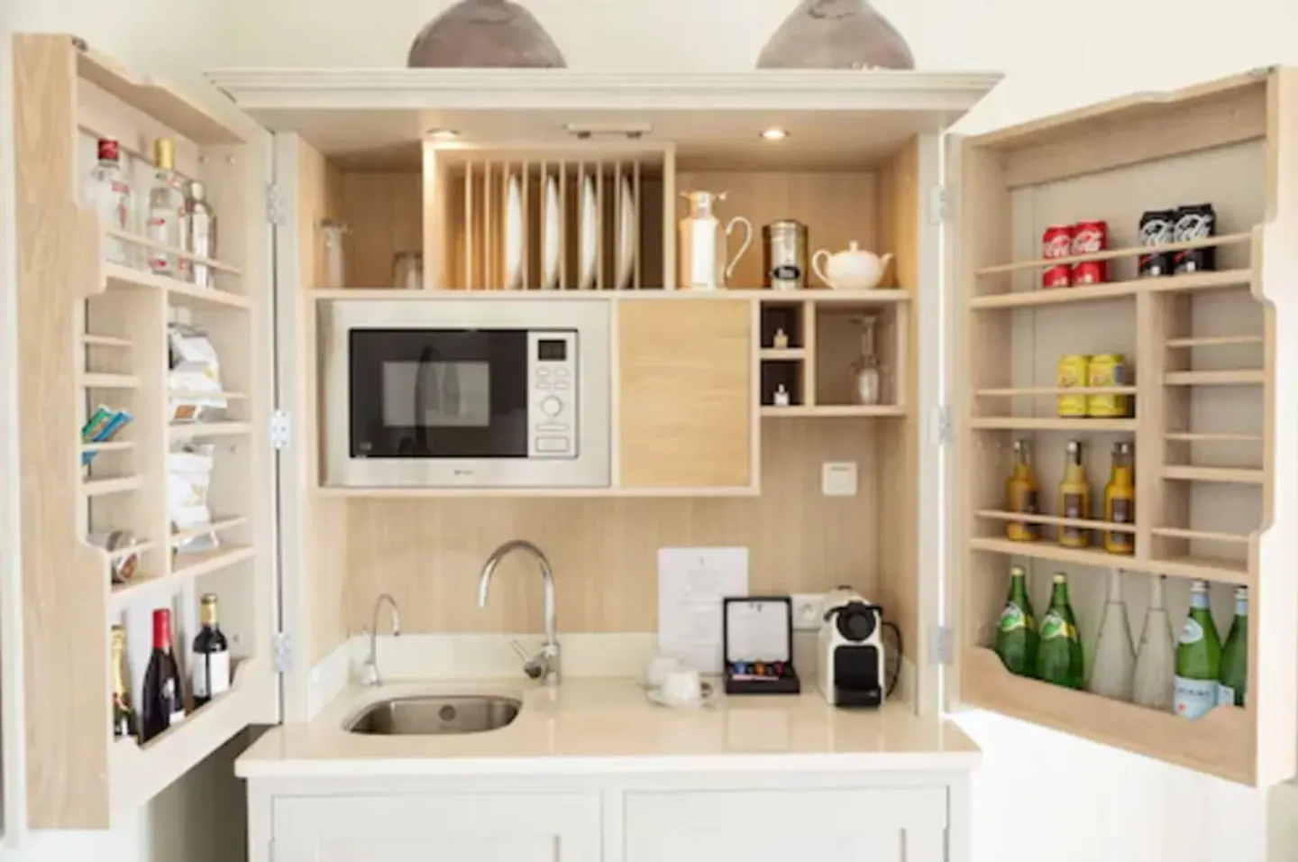 In-room kitchenette cabinet with sink, microwave, and minibar shelves at Le Toiny Hôtel & Beach Club.