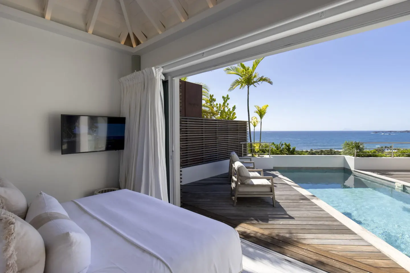 Guest room bed opening to a private pool and ocean view at Le Toiny Hôtel & Beach Club.