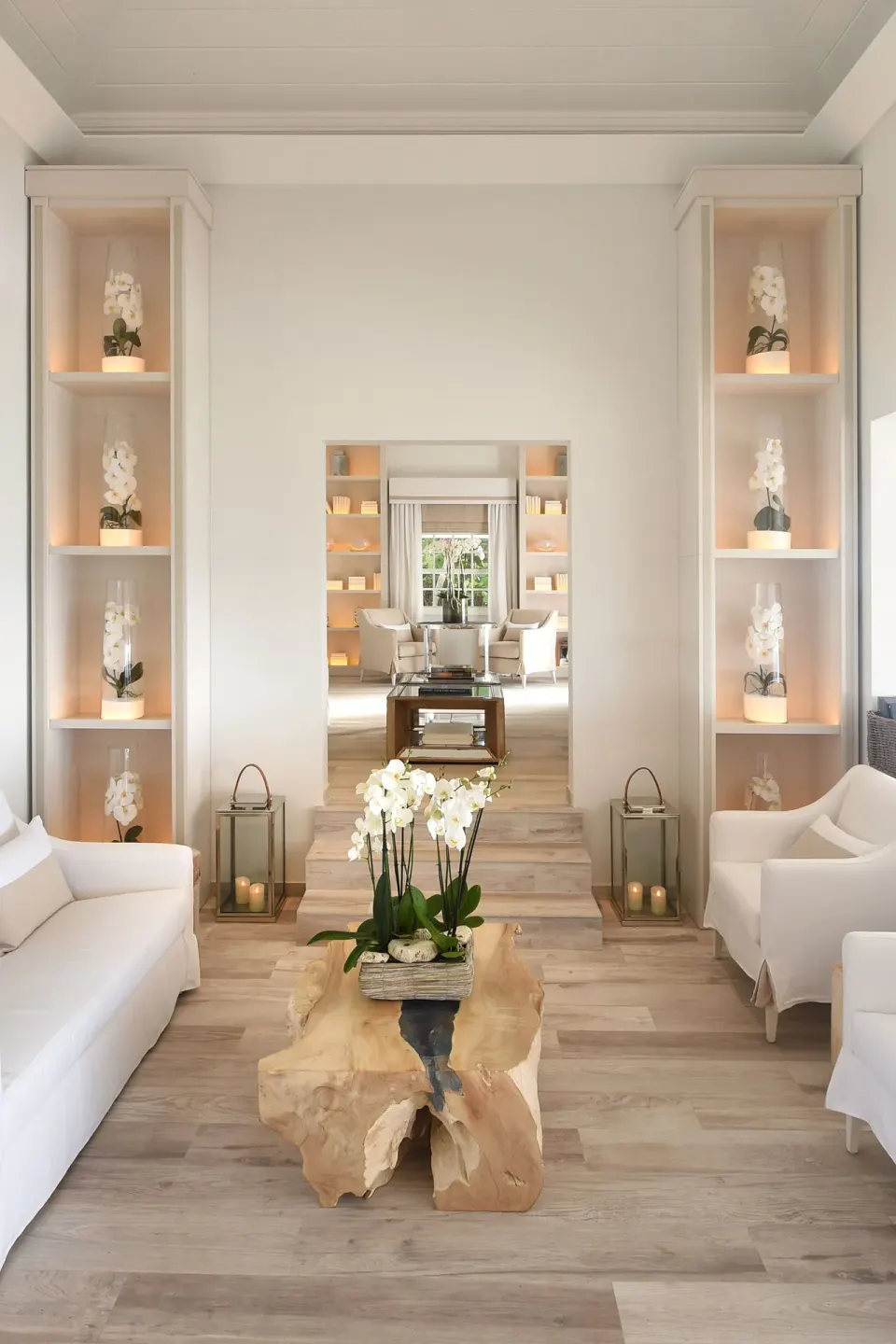 White lounge with orchids, sofas, lanterns, and a wood coffee table at Le Toiny Hôtel & Beach Club.