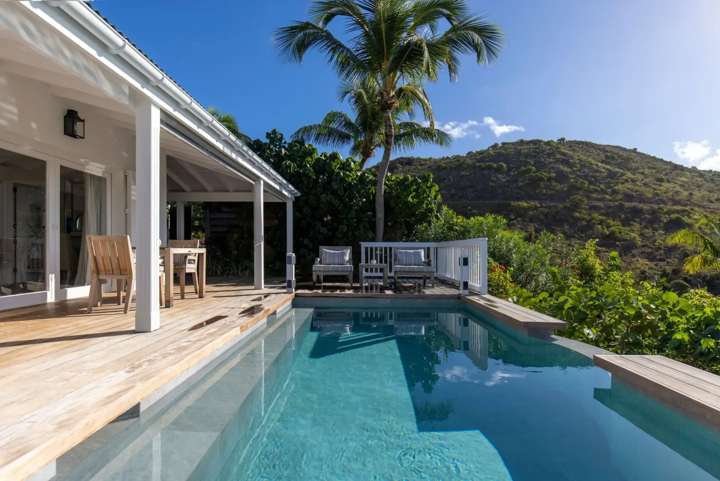 Private pool beside a white villa and palm tree at Le Toiny Hôtel & Beach Club.
