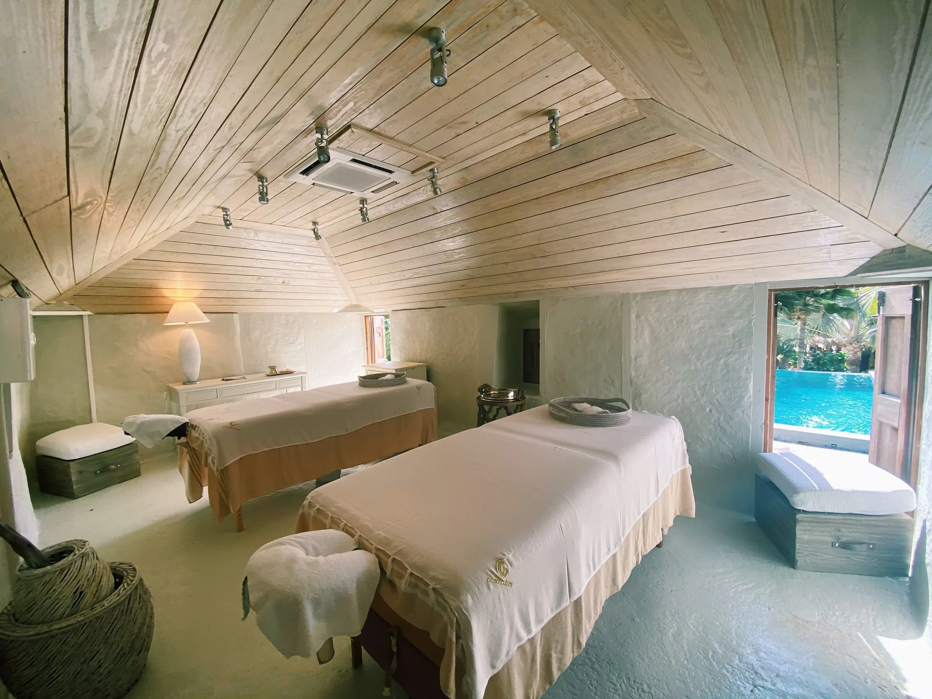 Spa treatment room with two massage tables and a poolside doorway at Le Toiny Hôtel & Beach Club.