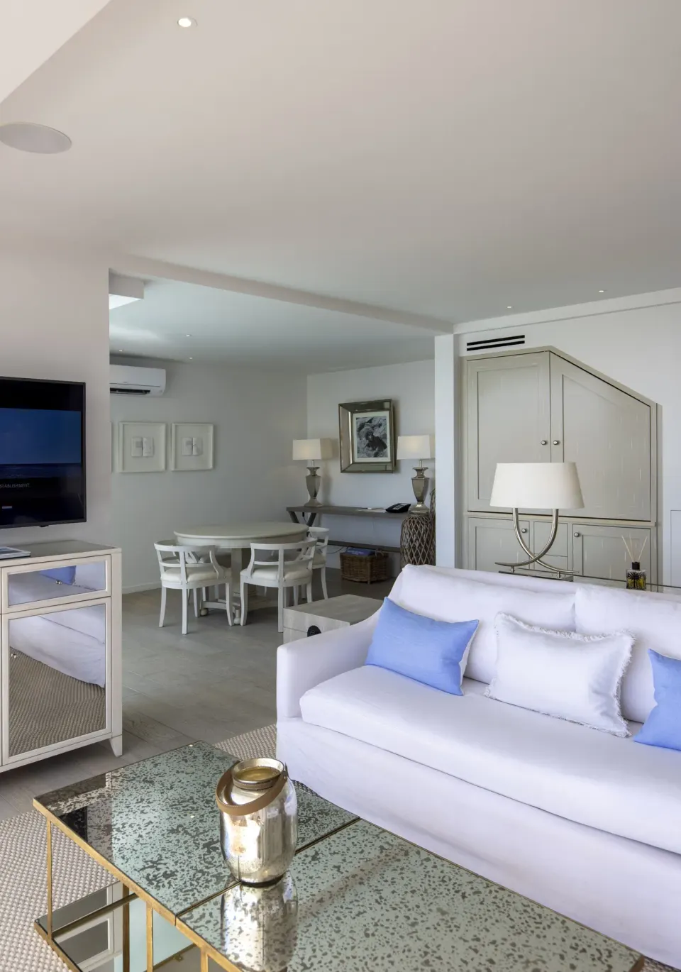 Suite lounge with white sofa, dining table, and mirrored coffee table at Le Toiny Hôtel & Beach Club.