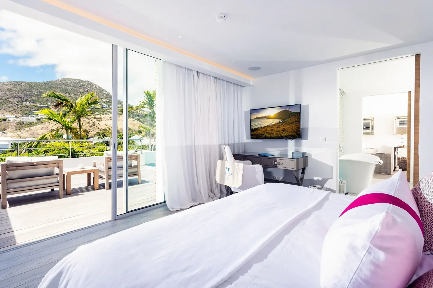 Guest room bed, desk, terrace, and open bathroom at Le Toiny Hôtel & Beach Club.