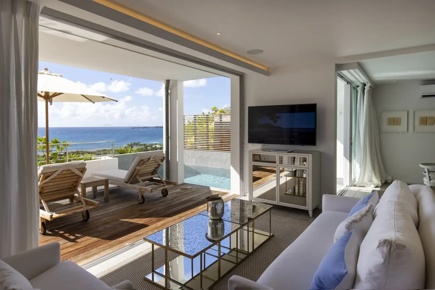 Villa lounge opening to a pool terrace and ocean view at Le Toiny Hôtel & Beach Club.