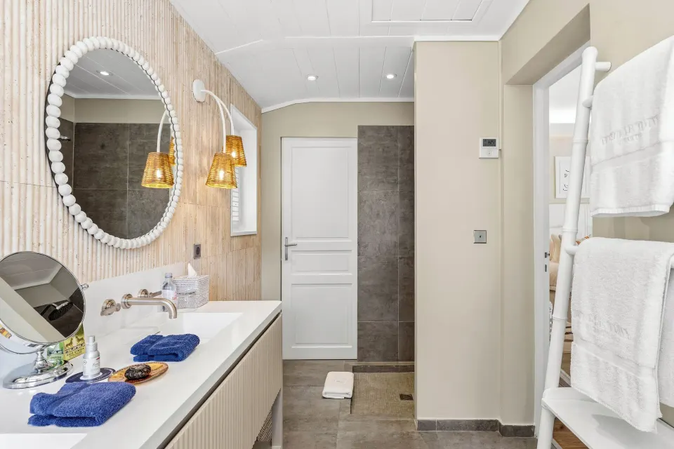 Junior Suite bathroom vanity at Le Toiny Hôtel & Beach Club with round mirror and towel ladder.