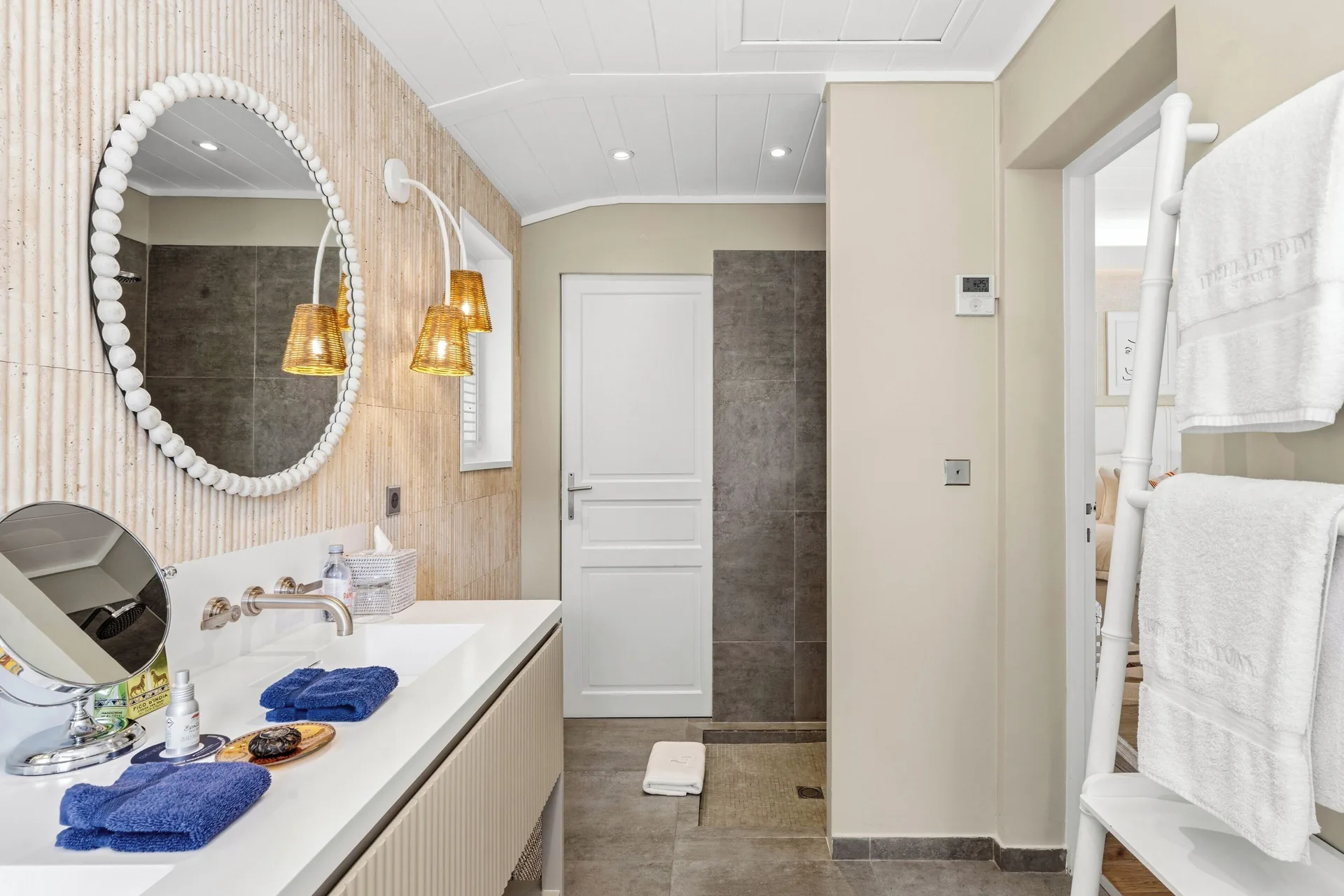Junior Suite bathroom vanity at Le Toiny Hôtel & Beach Club with round mirror and towel ladder.