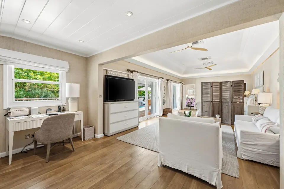 Junior Suite sitting area with desk, TV, and terrace doors at Le Toiny Hôtel & Beach Club.