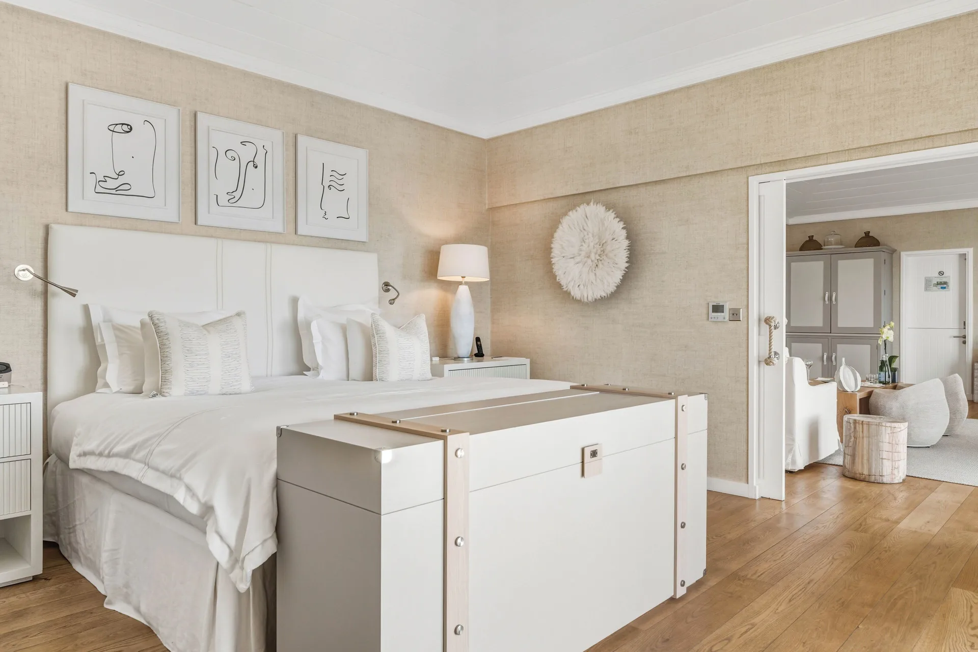 White bed in a Signature Family Suite at Le Toiny Hôtel & Beach Club with framed art and an adjoining room.
