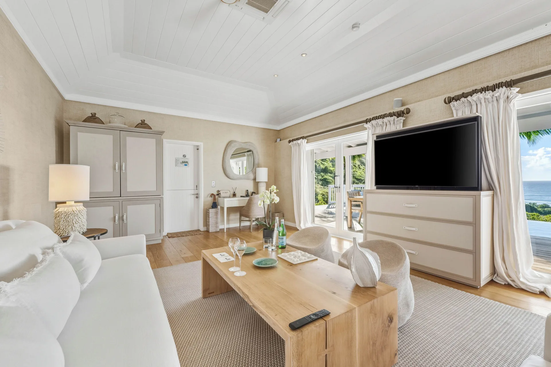 Signature Family Suite at Le Toiny Hôtel & Beach Club with sofa, TV, desk, terrace doors, and ocean view.