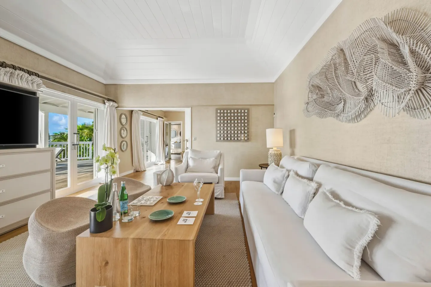 Living room in a Signature Family Suite at Le Toiny Hôtel & Beach Club with sofa, TV, and terrace doors.