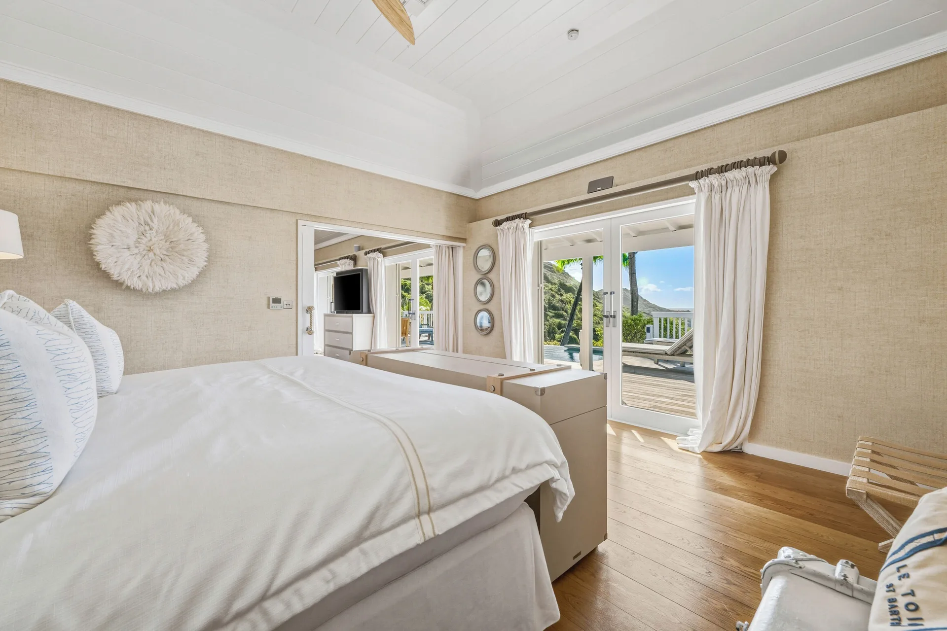 Signature Suite ocean view king bed beside terrace doors at Le Toiny Hôtel & Beach Club.