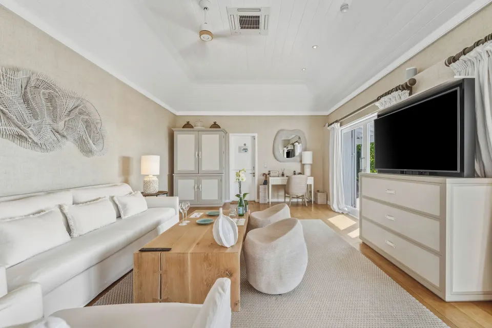 Signature Suite ocean view sitting area with sofa and TV at Le Toiny Hôtel & Beach Club.