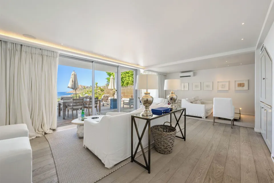 White villa living room with terrace access and ocean glimpse at Le Toiny Hôtel & Beach Club.