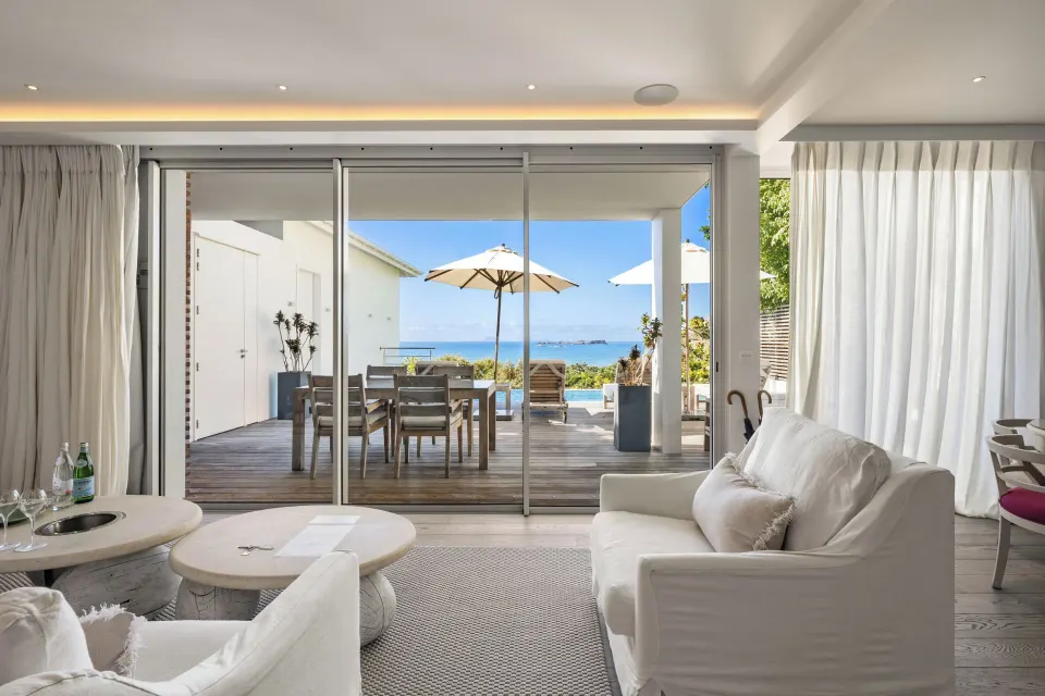 Living room with sofas opening to a deck and ocean view at Le Toiny Hôtel & Beach Club.