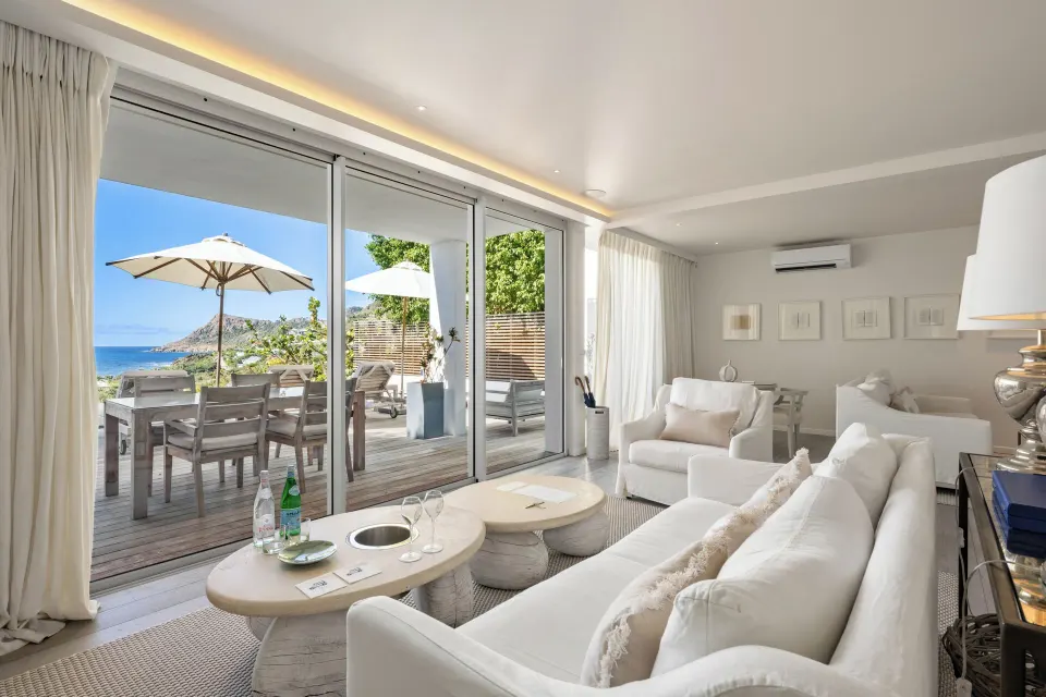 Living room with white sofa and doors to an ocean-view deck at Le Toiny Hôtel & Beach Club.