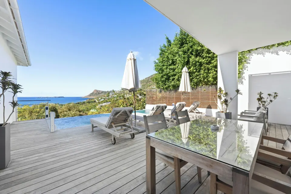 Ocean-view terrace with pool, dining table, and loungers at Le Toiny Hôtel & Beach Club.
