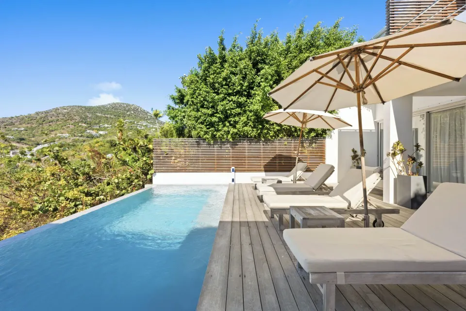 Private pool with loungers, umbrellas, and hillside views at Le Toiny Hôtel & Beach Club.