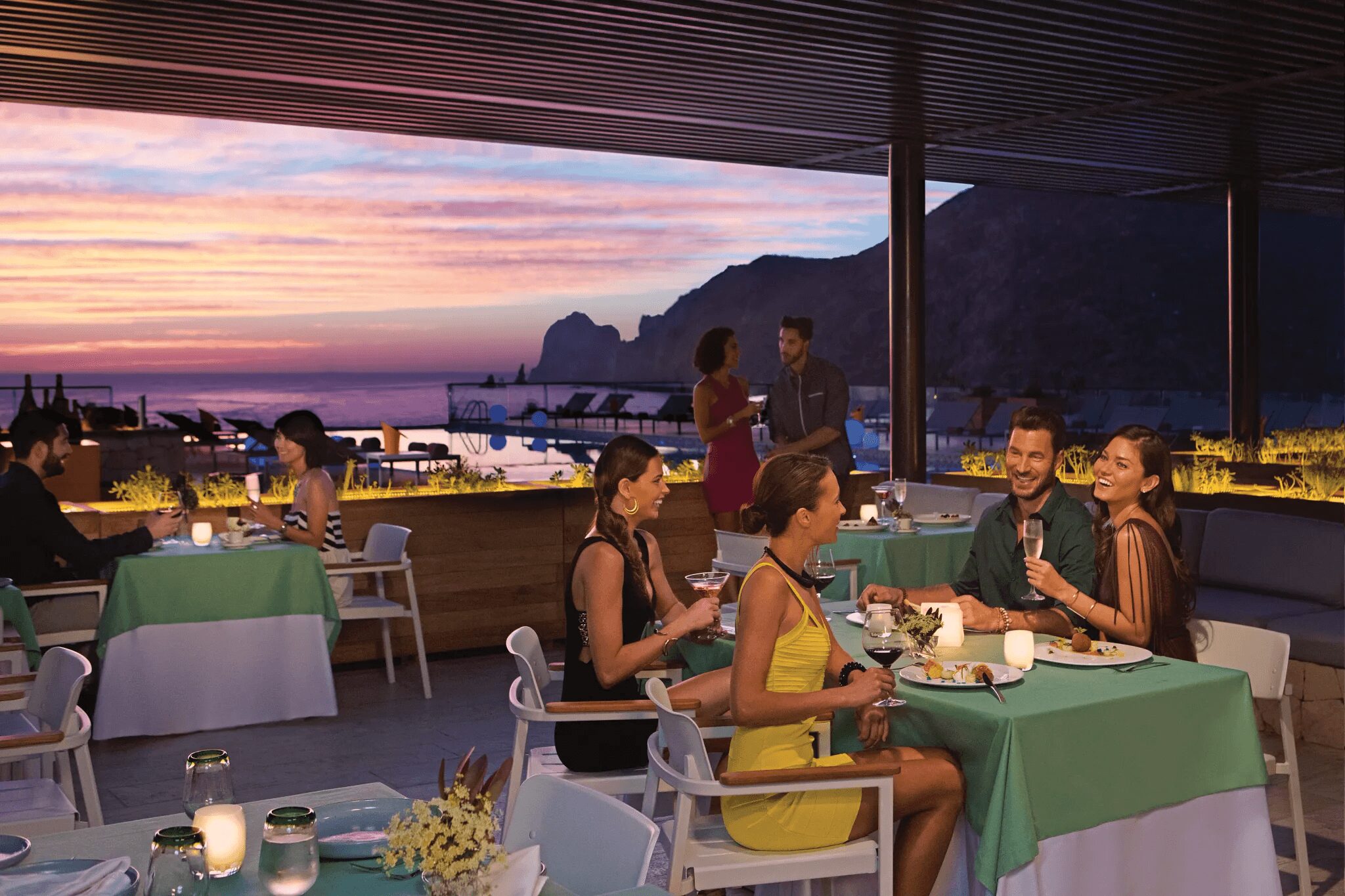 Elegant indoor dining at Kibbeh Restaurant at Breathless Cabo San Lucas overlooking the Marina and Sea of Cortez at sunset.